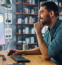 Man working at a computer showing a product page for a jacket