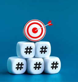 Photo is dice stacked into a pyramid shape with a red target at the top