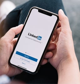 Person holding a phone with the LinkedIn sign up page on the screen