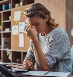 Woman holding her head in front of a desktop computer