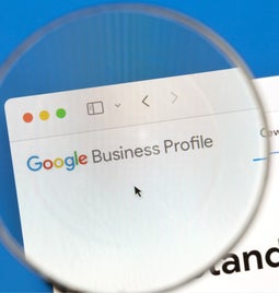 Magnifying glass hovering over a browser showing the Google Business Profile homepage