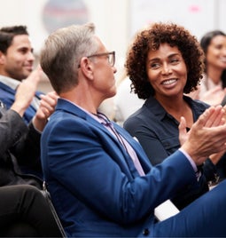 Businessmen and women sat down at a conference and clapping