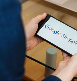 man holding phone with google shopping logo on it