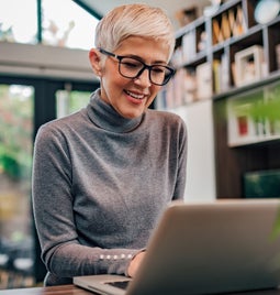 Woman with glasses working at a laptop in her home
