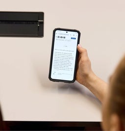 Over the shoulder view of two people looking at a smartphone displaying an article, sharing an interesting topic together.