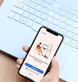 A hand holding a phone with the LinkedIn login page on screen