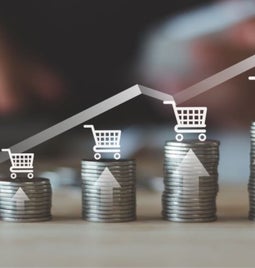 A stack of coins illustrating increasing growth, with shopping carts and upward arrows symbolizing rising sales or investments.