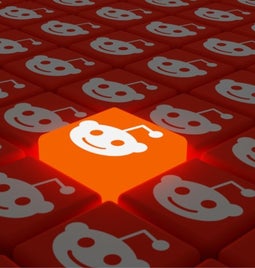 Rows of red cubes with the Reddit logo on with one cube raised higher and glowing in light