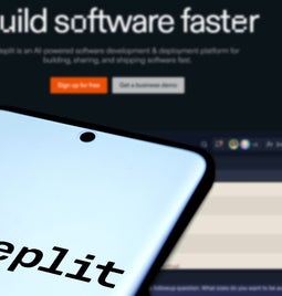 A smartphone displaying the Replit logo, with a dark website background promoting software development tools.