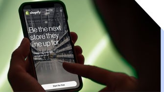 Person holding smartphone displaying Shopify website with the message: 