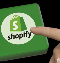 Hand pointing to the Shopify logo on a green cube