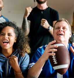 A group of football fans watching the TV and celebrating