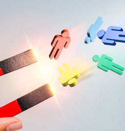 Magnet attracting small models of multi-colored people
