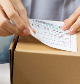Person placing a shipping label on a package