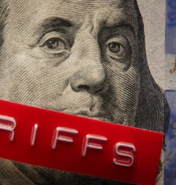 US money with a printed label on top saying tariffs