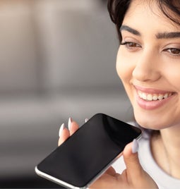 A woman holding a phone to her mouth for a voice search