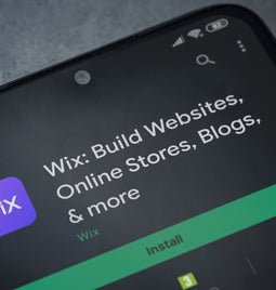 Wix app on a smartphone screen showcasing its features for building websites, online stores, and blogs, with an Install button.