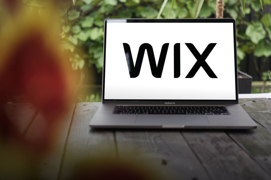 Laptop sat on a wooden bench with Wix logo on the screen